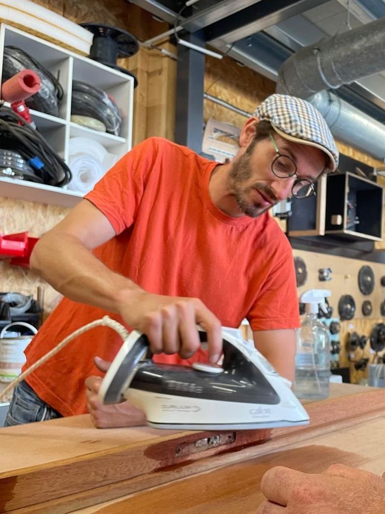 Térence redresse un enfoncement du bois à la vapeur à l'atelier
